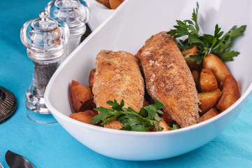 Grilled fish steak is served in batter with braised and roasted potato wedges. Mediterranean cuisine, European dish