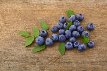 Fresh raw blueberries with leaves on white wooden background. Organic food