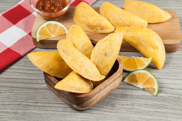 Tasty colombian food, fried empanada; photo on wooden background.