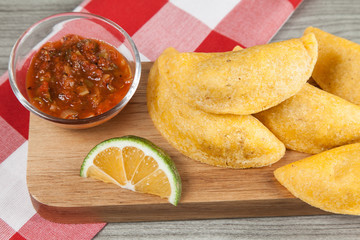 Tasty colombian food, fried empanada; photo on wooden background.