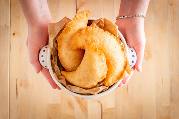 Female hands holding a bowl full of fried panzerotto. Traditional food of Puglia, Italy