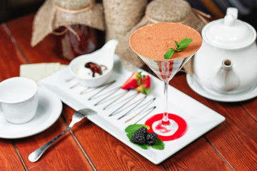 chocolate cake in a cocktail glass with nuts, sprinkled with sweet sauce with berries