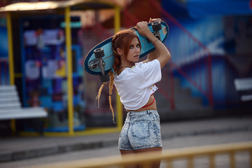 Girl holding skateboard in summer