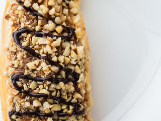 chocolate eclair sprinkled with nuts on a white plate