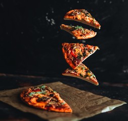Levitation pizza on black background - obrazy, fototapety, plakaty