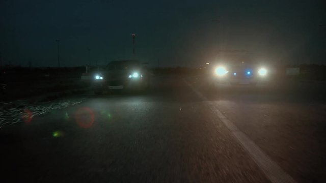 Police pursuit at night. Police in action. View of policemen chasing a young couple on sports car in the city.