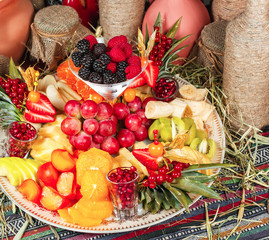  Fruit plate in Georgian style. Sliced ​​fruits - apple, banana, pineapple, orange, pear, grapes, persimmon, served with strawberries, raspberries, blackberries, blueberries in powdered sugar