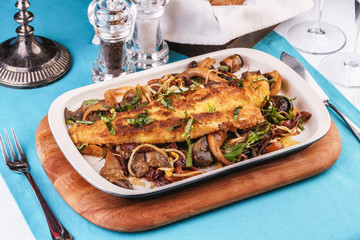 Seafood, Mediterranean cuisine. Grilled fish steak with mushrooms, oyster mushrooms, boletus, greens and onion rings. Caucasian kitchen