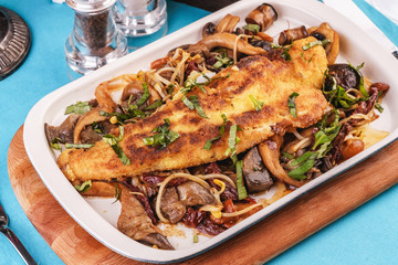 Seafood, Mediterranean cuisine. Grilled fish steak with mushrooms, oyster mushrooms, boletus, greens and onion rings. Caucasian kitchen