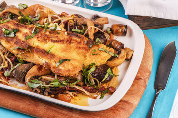 Seafood, Mediterranean cuisine. Grilled fish steak with mushrooms, oyster mushrooms, boletus, greens and onion rings. Caucasian kitchen