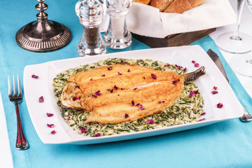 Fried steak of sea fish in batter, in a creamy sauce with greens and rose petals. Caucasian cuisine, Mediterranean food