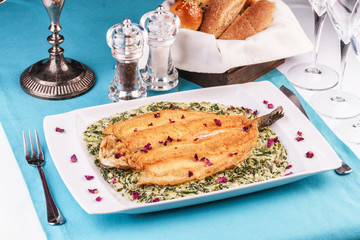 Fried steak of sea fish in batter, in a creamy sauce with greens and rose petals. Caucasian cuisine, Mediterranean food