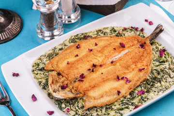 Fried steak of sea fish in batter, in a creamy sauce with greens and rose petals. Caucasian cuisine, Mediterranean food