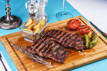 grilled beef steak with grilled pepper, onion rings and tomatoes. served with potato wedges and thyme. according to the Georgian recipe