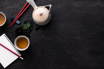 tea composition with ceramic tea cups and teapot on dark stone background