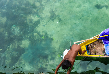 Semporna / Malaysia - Oct 4, 2013: Local young boy trying to get onshore on a small boat, Mabul...