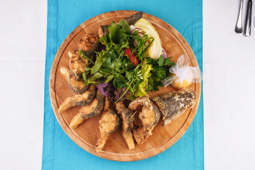 Seafood, Mediterranean cuisine. Grilled Seafood Steaks fish with herbs, carrots, tomatoes, cilantro, lemon and onions. Caucasian national cuisine