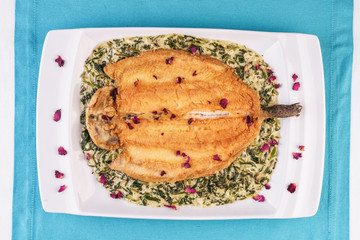 Fried steak of sea fish in batter, in a creamy sauce with greens and rose petals. Caucasian cuisine, Mediterranean food