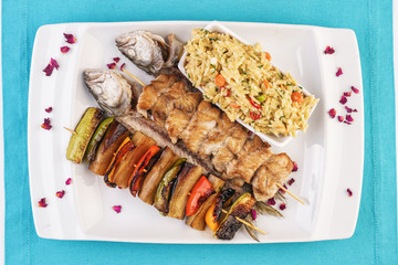 Mediterranean dish, Georgian recipe. Baked chicken skewers with lemon, vegetables, pepper, zucchini, eggplants and grilled tomatoes with spices, and steamed rice