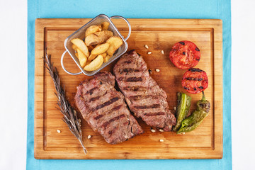 grilled beef steak with grilled pepper, onion rings and tomatoes. served with potato wedges and thyme. according to the Georgian recipe