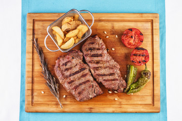 grilled beef steak with grilled pepper, onion rings and tomatoes. served with potato wedges and thyme. according to the Georgian recipe