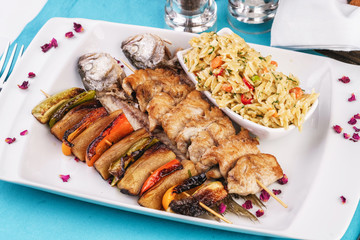 Mediterranean dish, Georgian recipe. Baked chicken skewers with lemon, vegetables, pepper, zucchini, eggplants and grilled tomatoes with spices, and steamed rice