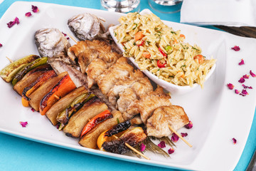 Mediterranean dish, Georgian recipe. Baked chicken skewers with lemon, vegetables, pepper, zucchini, eggplants and grilled tomatoes with spices, and steamed rice