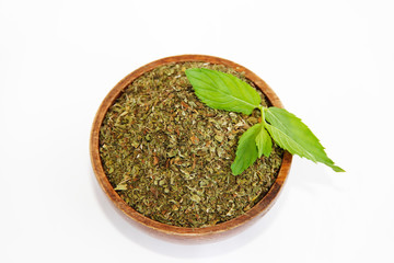 dried mint powder and natural green leaves of this plant in wooden plate