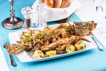 Seafood, Mediterranean cuisine. Baked fish with potatoes, onion rings, chili pepper, lemon and greens. Caucasian kitchen