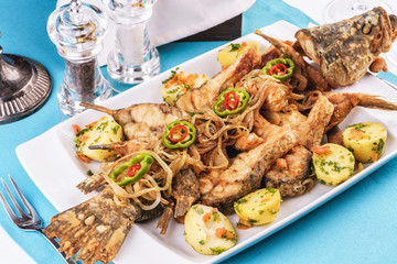 Seafood, Mediterranean cuisine. Baked fish with potatoes, onion rings, chili pepper, lemon and greens. Caucasian kitchen