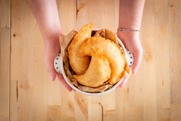 Female hands holding a bowl full of fried panzerotto. Traditional food of Puglia, Italy