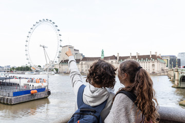 Two young teenagers stand indicate the London Eye - obrazy, fototapety, plakaty