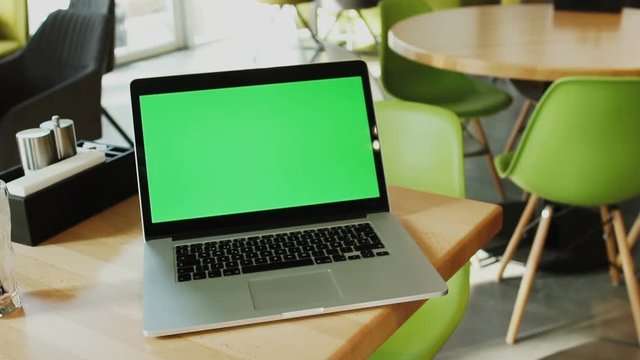 handshake of two men with background of computer with green screen on the table in cafe