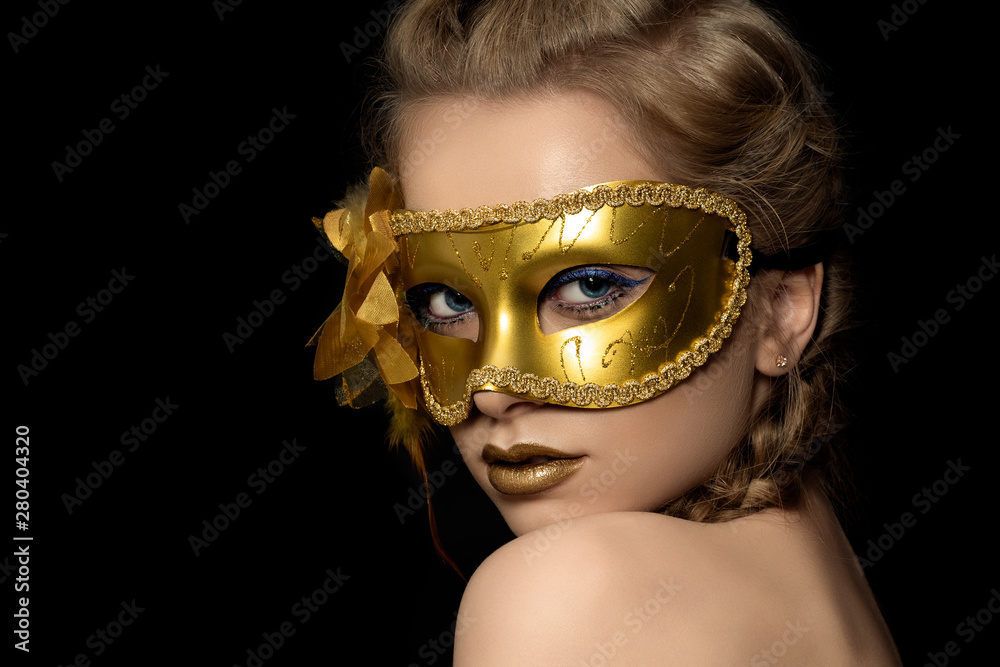 Wall mural Young beautiful woman wearing golden party mask