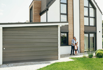Fototapeta na wymiar Pretty parent with child bought new home, standing on backyard house. Moving new modern house