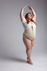 Fat lady with red hair posing for camera in studio