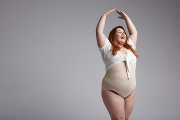 Plus size lady with red hair posing for camera in studio