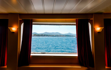 A view from the porthole window of a cruise ship, showing the sea and island. Summer travel