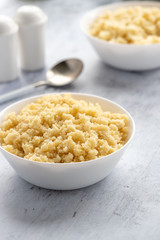 Cooked couscous in a white ceramic bowl on the table.