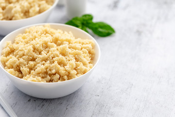 Cooked couscous in a white ceramic bowl on the table.