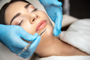 Beautician using blackhead remover to clean lady face