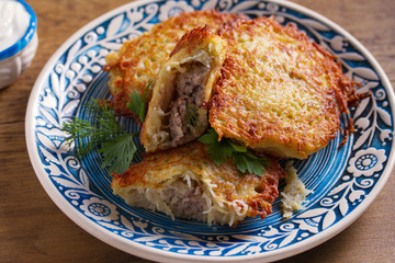 Potato Pancakes Filled With Meat. Vegetable fritters stuffed with meat. Latkes on blue plate