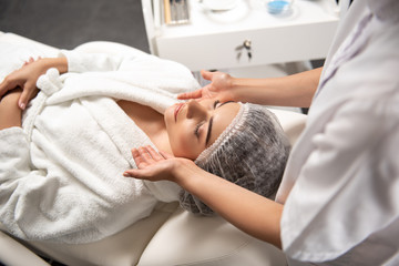 Obraz na płótnie Canvas Young woman getting face massage at modern spa salon