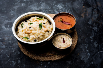 Ven pongal recipe is a popular South Indian food prepared with rice & moong dal and served with sambar and coconut chutney, selective focus