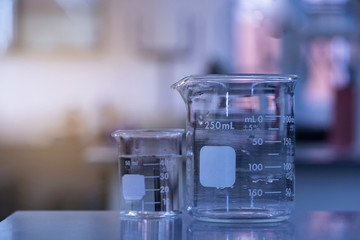 clear two glass beaker with water on laboratory table in blue science research background