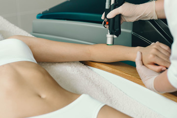 Fototapeta premium beautician removes hair on beautiful female hands using a laser. hair removal on the hands, laser procedure at clinic