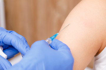 Doctor injecting a vaccine in arm close-up