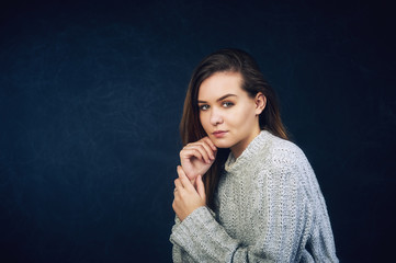 Fototapeta premium Studio portrait of a young beautiful girl in a warm knitted sweater . Warm comfortable casual clothes