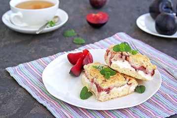 Sliced shortbread cake with curd cream and plum on a white plate. Sweet cakes. Harvest plums.
