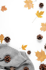 Workspace with golden maple leaves, cones, sweater on white background. Creative composition. Autumn or Winter concept. Flat lay, top view
